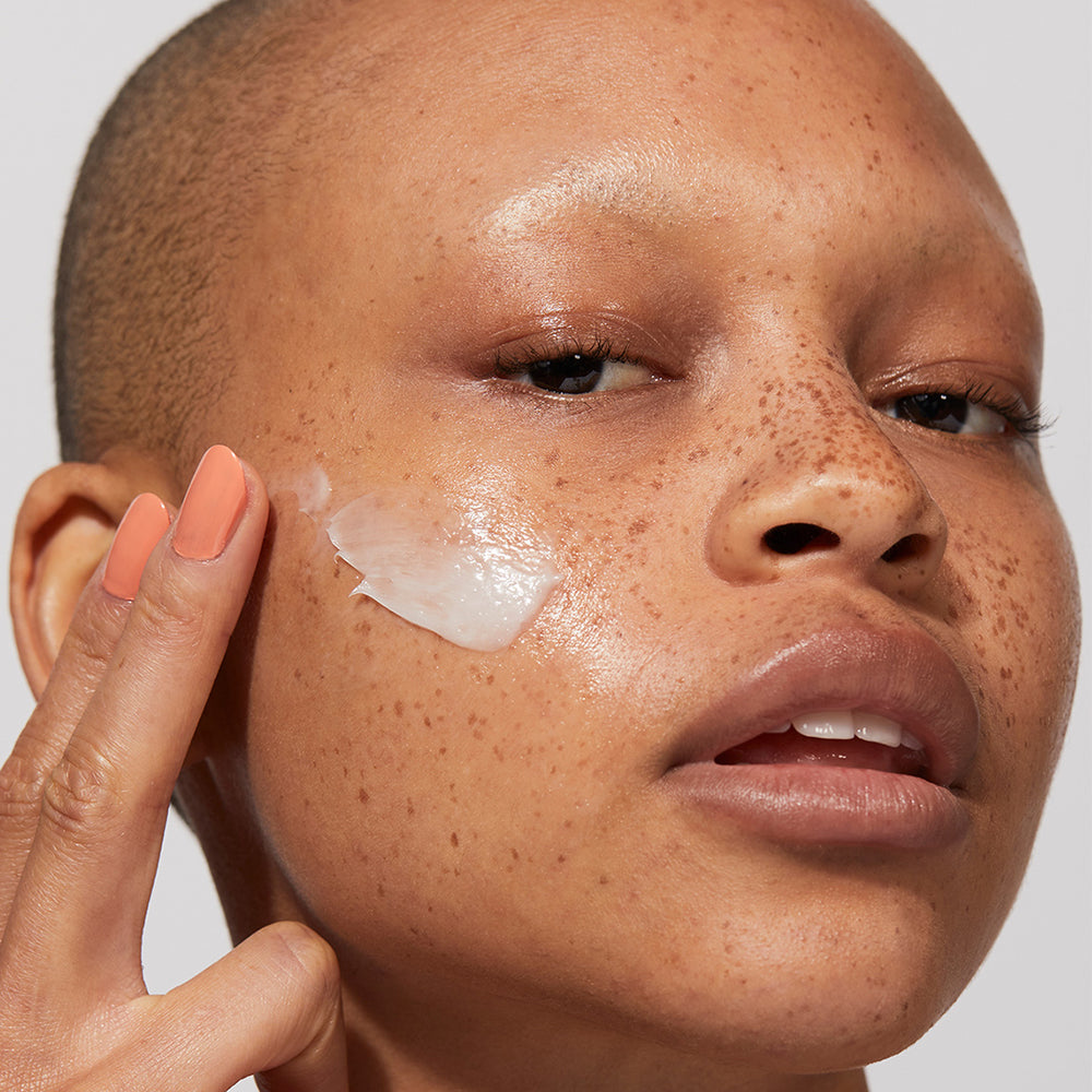 A model applying Jones Road Beauty's Light Moisture Cream onto their skin